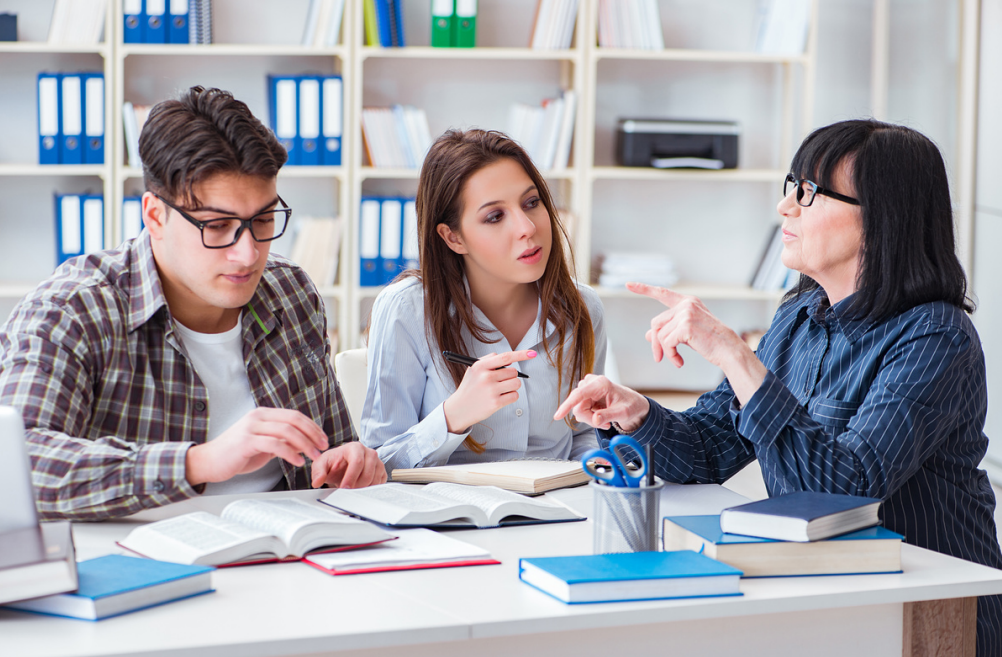 Nauczycielka udzielająca korepetycji dwojgu studentom.